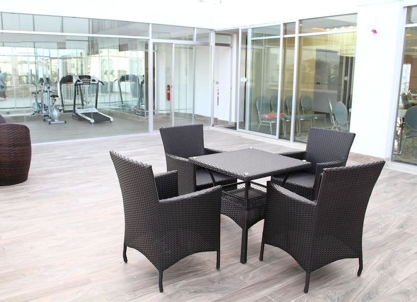 Blossom Hotel Dhaka patio with wicker seating outside a glass-walled gym