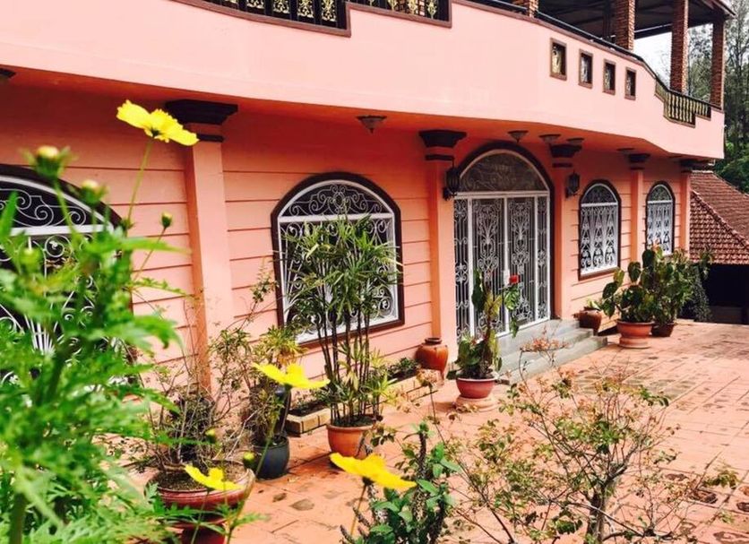 Memory Villa in Dalat, pink hotel exterior with arched windows, potted plants and terrace