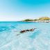 Amsterdam Manor Beach Resort in Noord, beachfront view with a person floating in clear turquoise water
