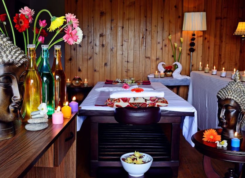 Summit Barsana Resort & Spa, Kālimpong spa room with Buddha statues, flowers, massage table and candles
