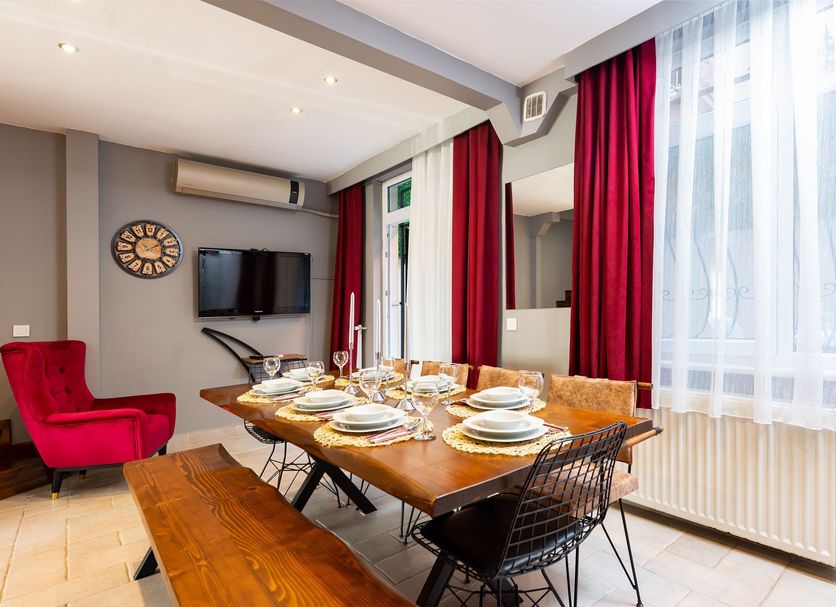 Bright Apart Hotel Istanbul dining area with set table, red curtains, wall TV, and large windows