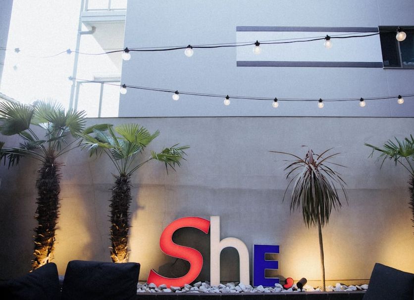 Hotel She, Osaka outdoor terrace with palm trees, string lights and illuminated sign