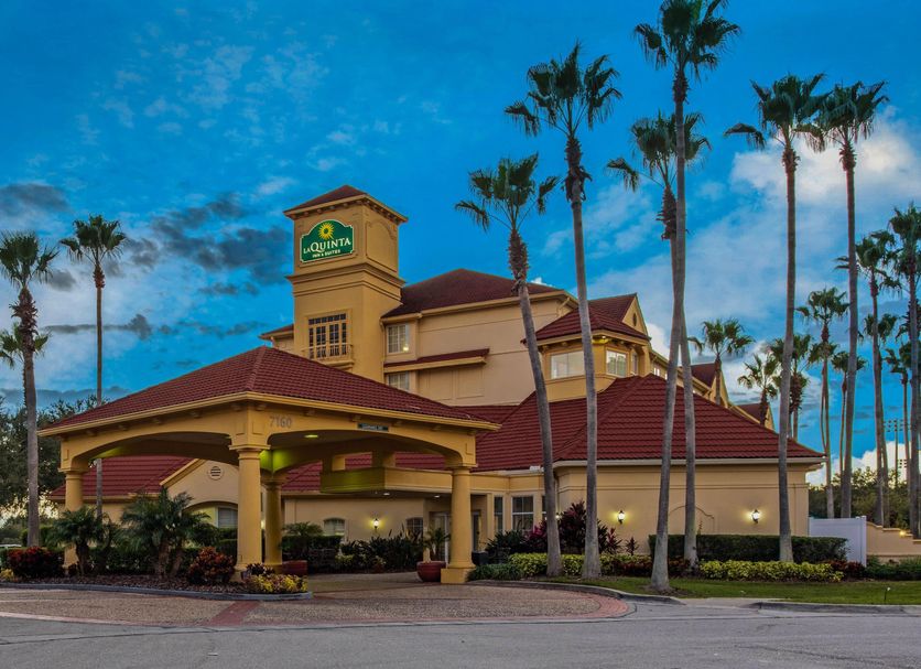 La Quinta Inn and Suites by Wyndham Orlando Airport in Orlando exterior with palm trees at dusk