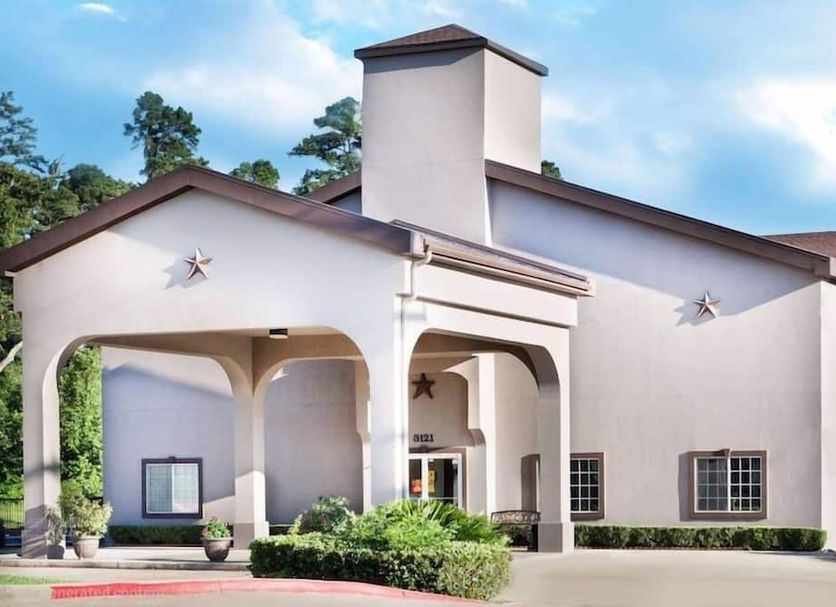 Hotel Piney Woods in Huntsville exterior with white stucco facade, covered entrance, and tower
