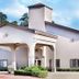 Hotel Piney Woods in Huntsville exterior with white stucco facade, covered entrance, and tower