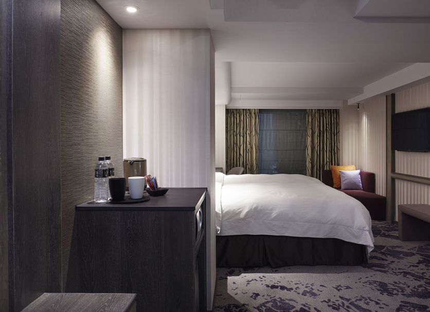 At Home Hotel Ximen in Taipei City guest room with bed, seating nook, and TV