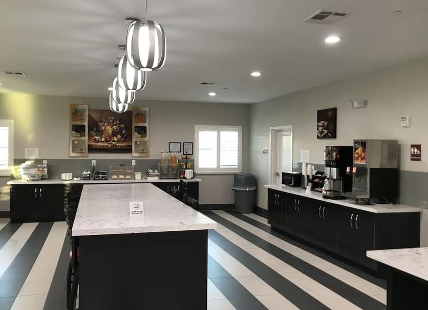 Grand Villa Inn & Suites Houston breakfast area with buffet counters and striped flooring