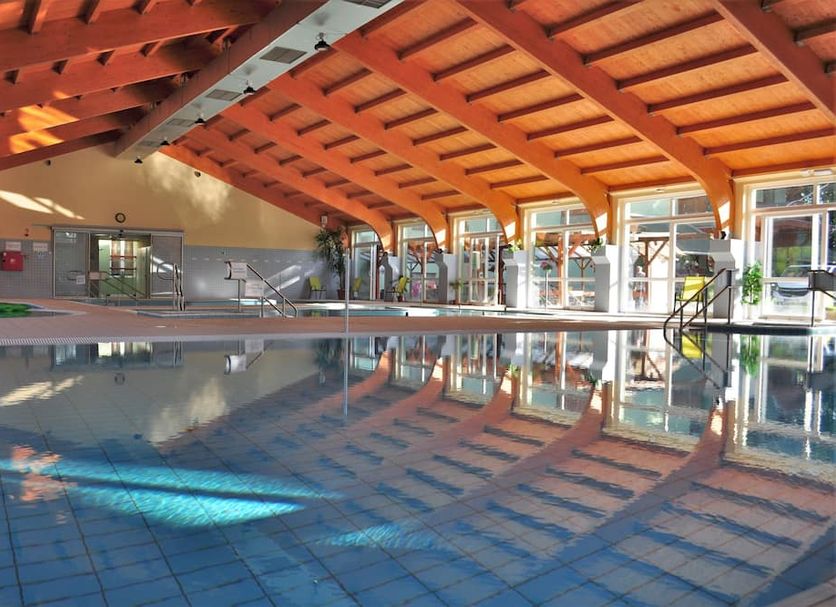 Indoor pool at Hotel Hajnal in Mezőkövesd with wood-beamed ceiling and large windows