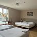 Hôtel La Métairie in Cordes-sur-Ciel with two beds, a window table, and simple bedroom decor
