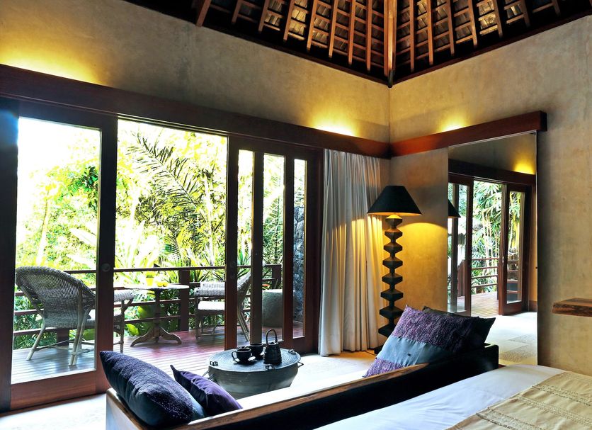 The Purist Villas & Spa Ubud villa bedroom with sliding doors to a private balcony and tropical greenery