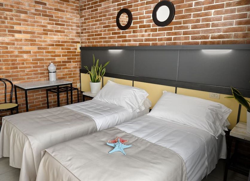 Hotel Marina, Marina di Massa: twin bed hotel room with brick wall and small table