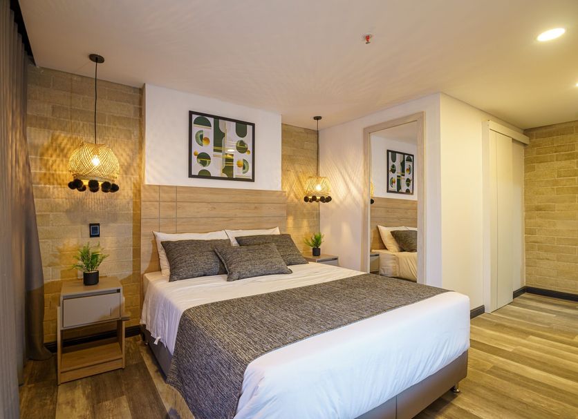 First Class Hotel Medellín guest room with king bed, warm lighting, and a mirrored doorway