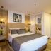 First Class Hotel Medellín guest room with king bed, warm lighting, and a mirrored doorway