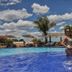 Frangipani Hotel Boutique in Brotas: couple standing in a resort pool with palm trees and blue sky