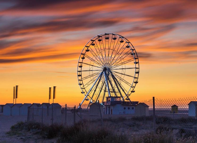 La Villa Andry in Ouistreham with a Ferris wheel silhouetted at sunset