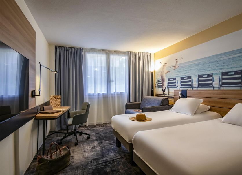 Novotel Antibes Sophia Antipolis room in Valbonne with twin beds, desk, chairs and a large window