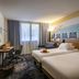 Novotel Antibes Sophia Antipolis room in Valbonne with twin beds, desk, chairs and a large window
