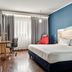 Holiday Inn Express Milan - Malpensa Airport room with queen bed, desk, chair and red lounge chair