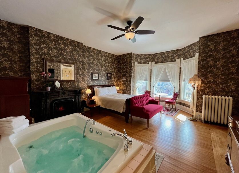 The Ludington House, Ludington: room with whirlpool tub, four-poster bed, bay windows and red loveseat