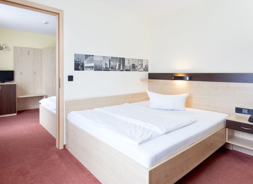 Mit-Mensch Berlin guest room with double bed, bedside light, and adjoining bathroom doorway