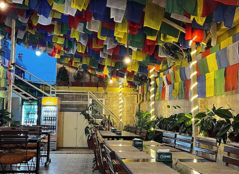 Boudha Stupa View Guest House in Kathmandu patio with colorful prayer flags, tables, benches, and plants