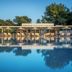 Hotel Kanali in Kanali: outdoor pool with palm trees, umbrellas, loungers, and reflected sky