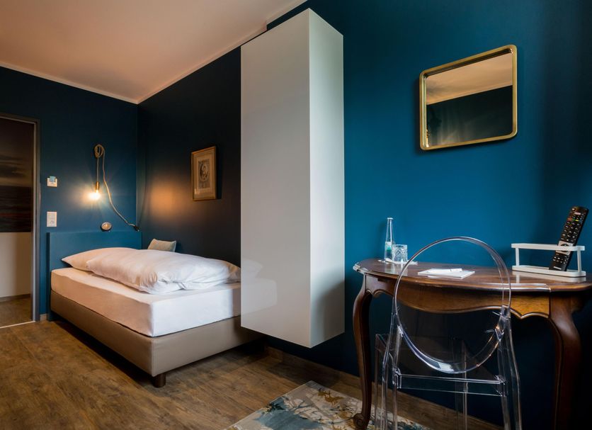 Hotel Heimathafen Lörrach guest room with single bed, desk and teal walls