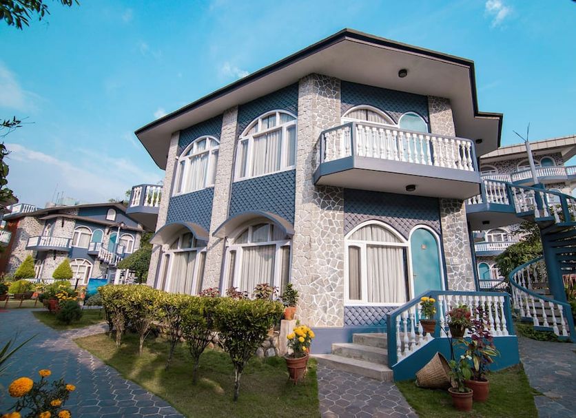 Hotel The Kantipur in Pokhara: two-story hotel with balconies, garden path, and blue sky