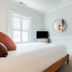 Ellery Hotel Provincetown guest room with bed, TV, round mirror, and open bathroom door in Provincetown