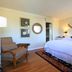 The Tides Laguna Beach guest room with king bed, sitting chair, lamps, and coastal wall decor