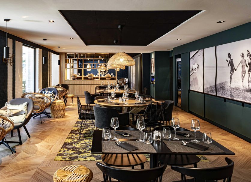 Novotel Lens Noyelles restaurant with set tables, woven chairs and large wall art in Noyelles-Godault