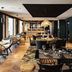 Novotel Lens Noyelles restaurant with set tables, woven chairs and large wall art in Noyelles-Godault