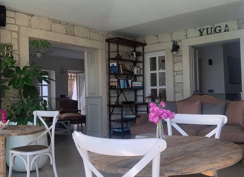 Yuga Alacati in Alacati: stone patio seating with round tables, white chairs, and lounge seating