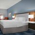 Hampton Inn Russellville guest room with king bed, wall-mounted TV, and armchair