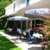 Hotel zum Rosenteich in Bad Zwischenahn with outdoor patio dining and umbrellas beside a green garden