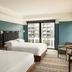 The Junto in Columbus guest room with two beds and city-view balcony doors
