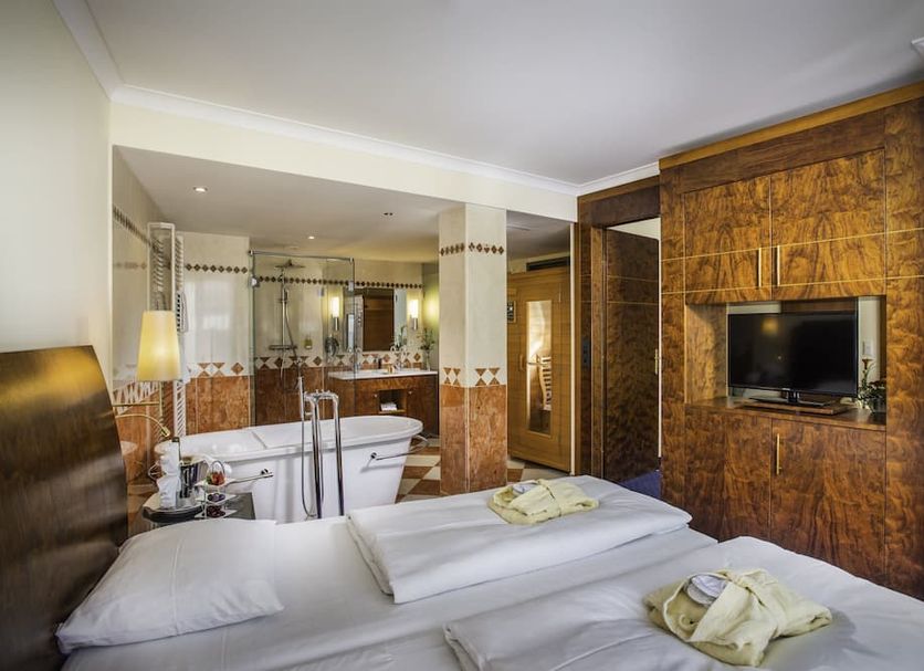 Hotel Glöcklhofer in Burghausen: guest room with bed, bathtub and wall-mounted TV