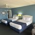 Shoreline Island Resort in Madeira Beach guest room with two beds, lamp and recliner against blue walls.