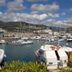 Hotel Excelsior in Loano with marina boats and mountains under a partly cloudy sky