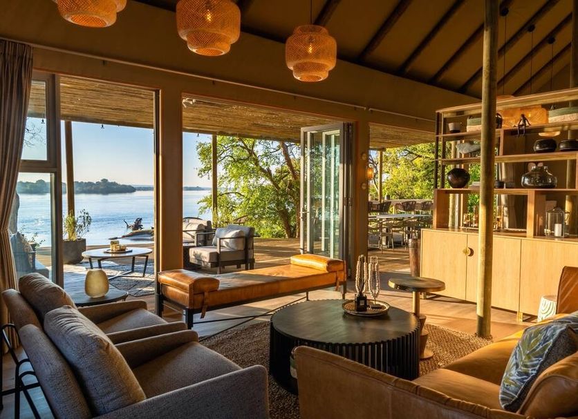 Victoria Falls River Lodge lounge with river views, open doors, and wood deck seating in Victoria Falls