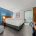 Baymont by Wyndham Tuscaloosa guest room with king bed, armchair and ensuite bathroom door