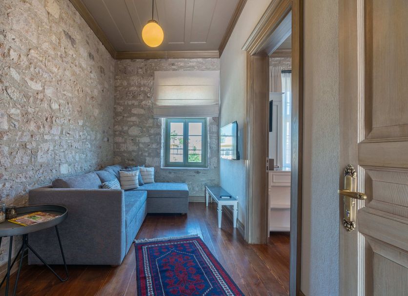 Elia Hotel Cunda by Ortunc in Ayvalik, cozy guest room with stone wall, sofa, rug and window view