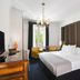 Melia Paris Champs Elysees room in Paris with king bed, chandelier, armchairs and tall window