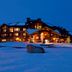 Waldorf Astoria Park City exterior at dusk with warm lights, snowy grounds and mountain backdrop