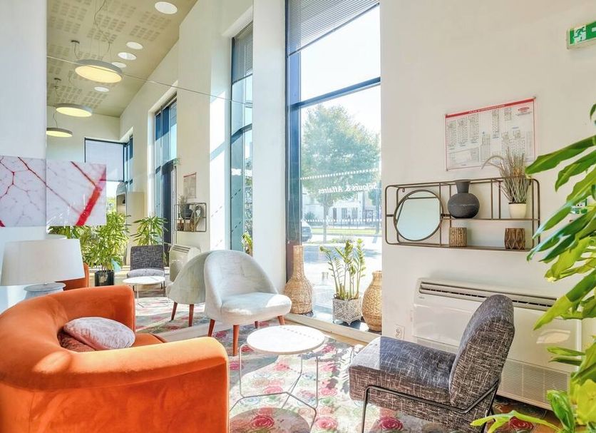 Séjours & Affaires Paris-Vitry lobby with colorful chairs, large windows, and potted plants in Vitry-sur-Seine