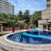 Puteri Bay Hotel in Malacca features a circular outdoor pool beside a beige building and palm trees.