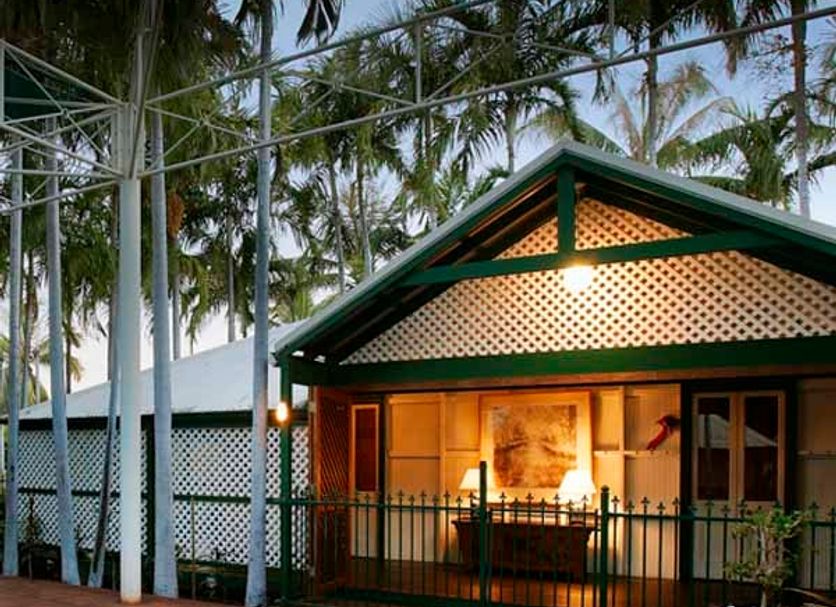 Pinctada Mcalpine House, Broome: poolside bungalow with lit veranda and palm trees