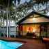 Pinctada Mcalpine House, Broome: poolside bungalow with lit veranda and palm trees