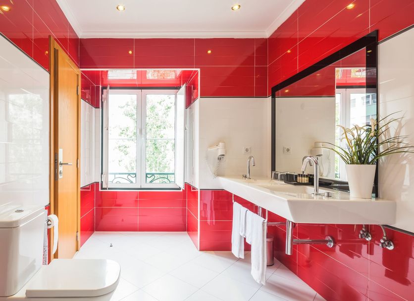 Vila Nova Guesthouse bathroom in Lisbon with red tile walls, walk-in shower, and white sink vanity