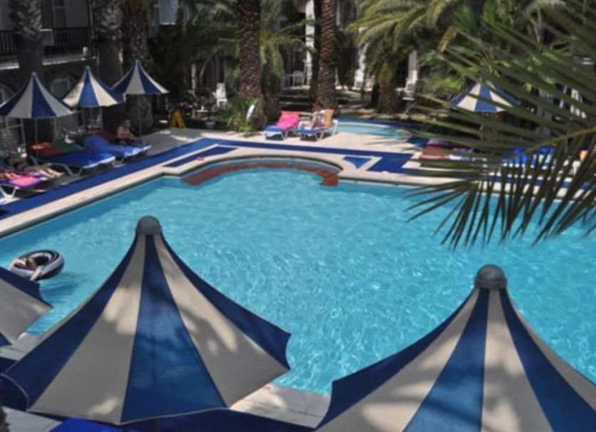 Sami Plaza in Bodrum, outdoor pool with blue-and-white sun umbrellas and palm trees